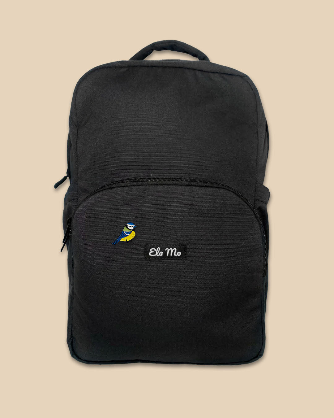 Ela Mo™ Pin für Rucksäcke - Meise auf schwarzem Rucksack vor gelbem Hintergrund