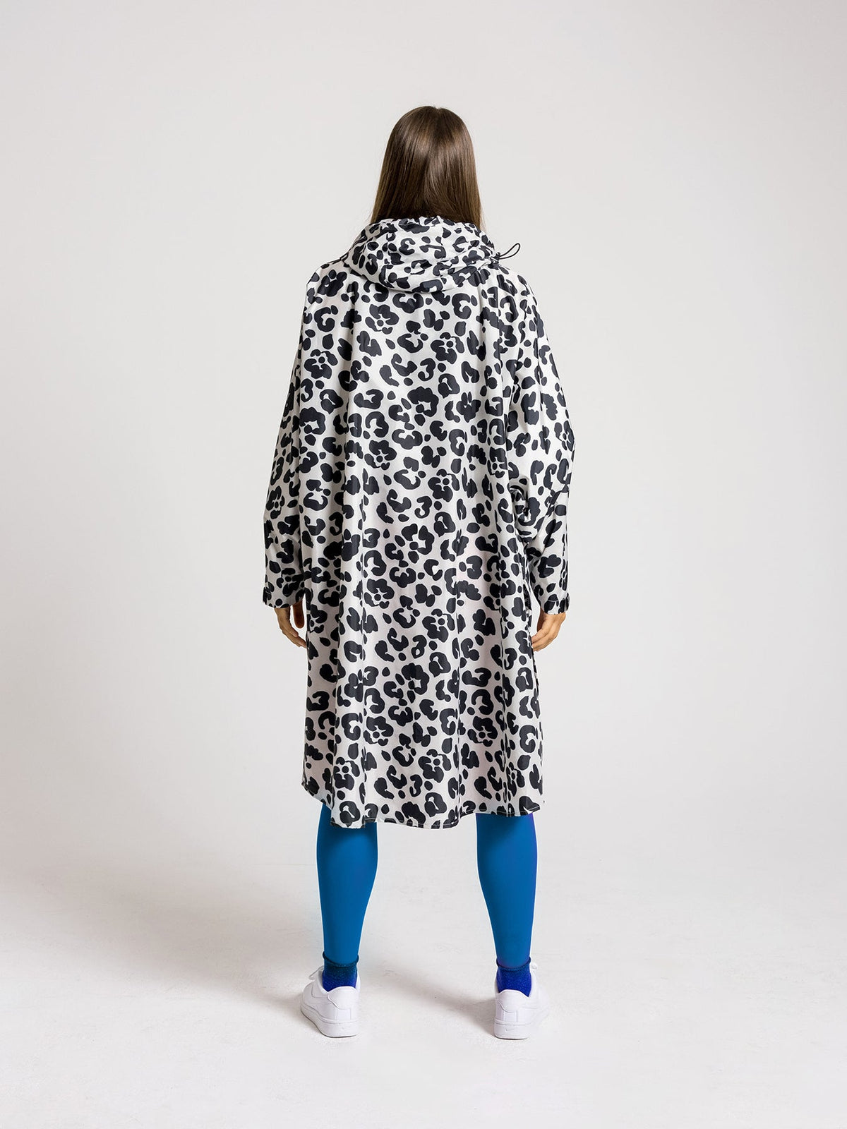 Ela Mo™ Regenponcho | Leo. Frau mit Regenponcho von hinten auf weißem Hintergrund.
