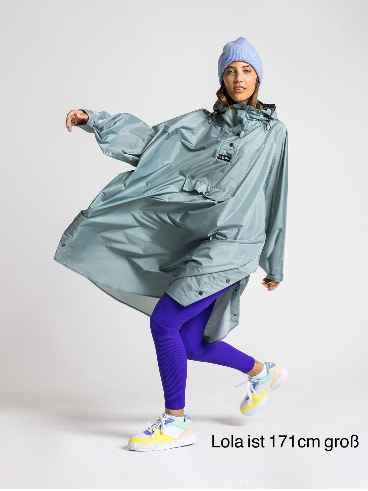 Ela Mo™ Regenponcho | Mint. Eine Frau mit Regenponcho, inklusive Produkt-Höhenangabe.
