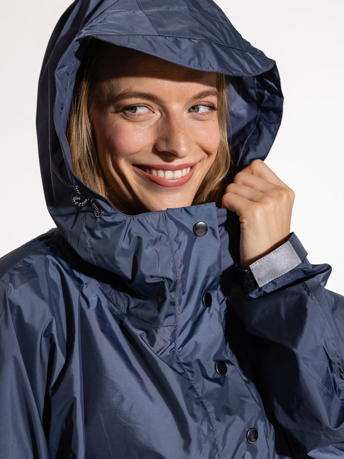 Ela Mo™ Regenponcho | Navy. Eine Frau im Regenponcho mit hohem Kragen und Kaputze.