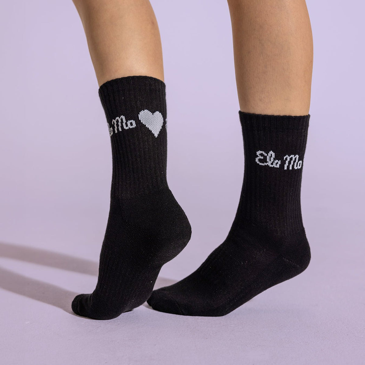 Ela Mo™ Socken aus Bio-Baumwolle-Eine Person in schwarzen Ema-Mo-Socken vor helllila Hintergrund.