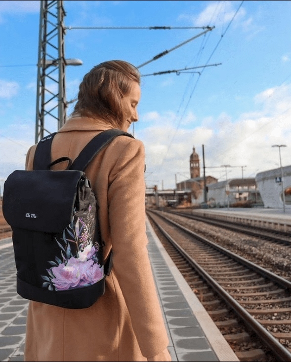 Ela Mo™ Daypack Rucksack | Beauty in Darkness. Eine Frau mit dem Rucksack auf dem Rücken im Freien.