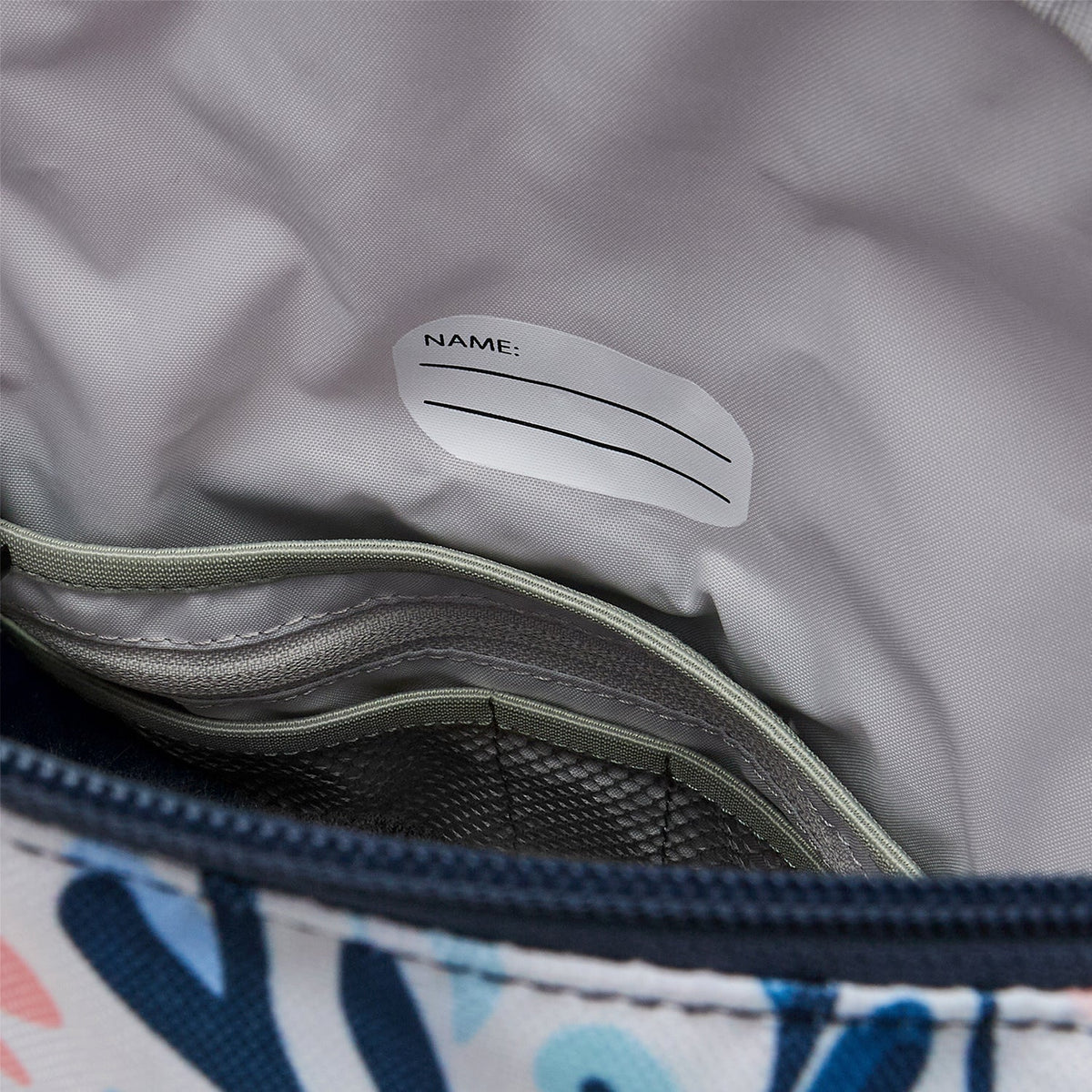 Ela Mo™ Kinderrucksack (6-10 Jahre) | Pastel Land. Hellgrauer Innenbereich mit kleinen Fächern und Namensschild.