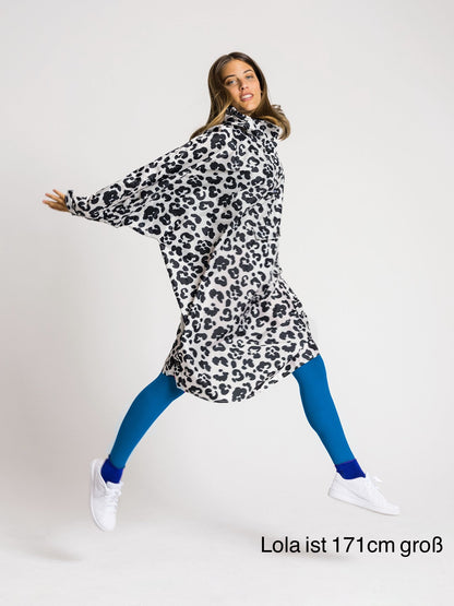 Ela Mo™ Regenponcho | Leo. Eine Frau mit Regenponcho, inklusive Produkt-Höhenangabe.