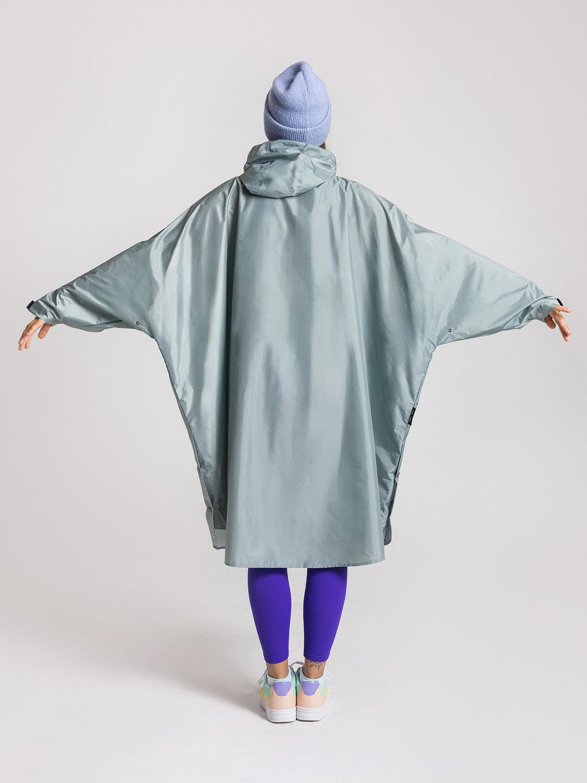 Ela Mo™ Regenponcho | Mint. Frau mit Regenponcho von hinten auf weißem Hintergrund.