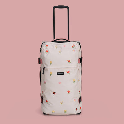 Ela Mo™ Reisetasche mit Rollen 78 Liter | Embroidery Edition Losy. Helle geblümte Tasche mit Tragegriff auf rosa Hintergrund.