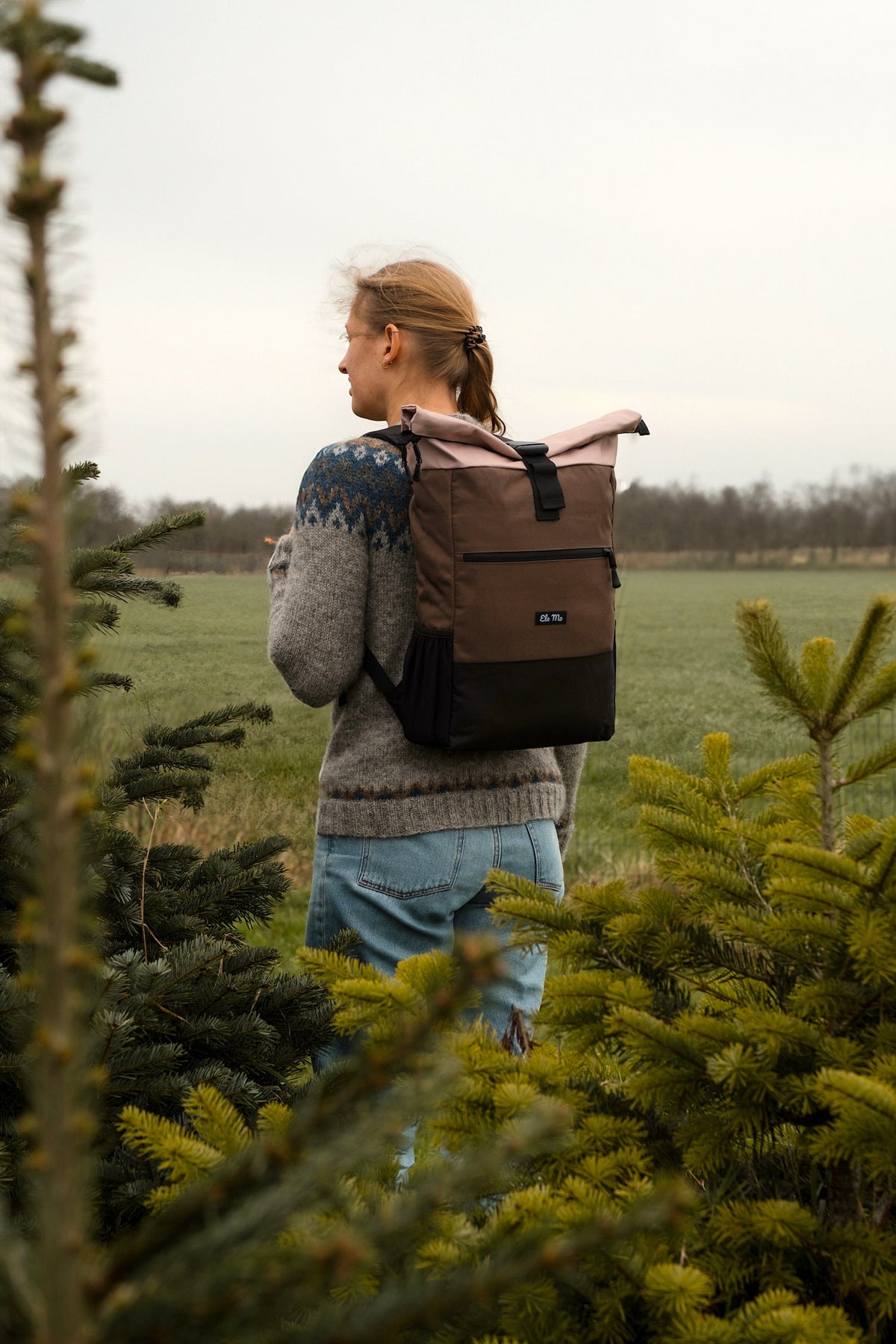 Ela Mo™ Rolltop Rucksack | Sand and Olive. Eine Frau mit dem braunen Rucksack auf der Wiese.